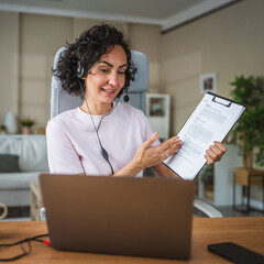 woman work from home wearing headset talk with client on video call