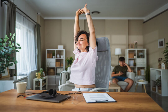 Mature curly hair woman stretching at home office happy and relax - Powered by Adobe