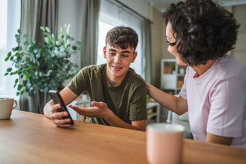 teenage boy share good news from mobile phone with his happy mother