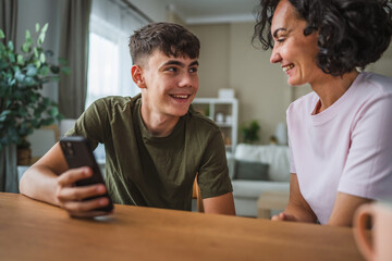 teenage boy share good news from mobile phone with his happy mother