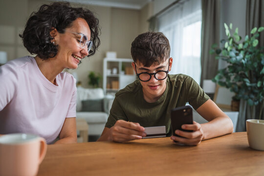 mom and son shopping online together, use mobile phone and credit card