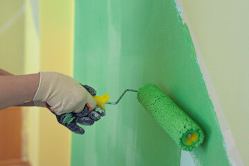 The process of interior painting of walls with a roller in the room. The concept of room renovation.