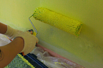 The process of interior painting of walls with a roller in the room. The concept of room renovation.