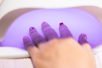Home nail salon beauty treatment fashion art with hand under UV light curing nail polish for perfect manicure and stylish nail art design