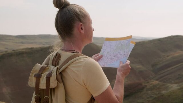 Woman tourist using paper map travels in mountains.