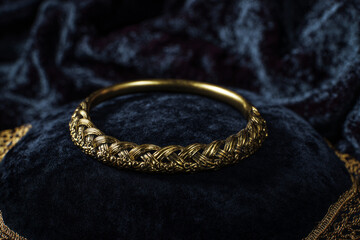 Beautifully crafted golden bangle displayed on a dark velvet surface, highlighting intricate design and luxurious appearance