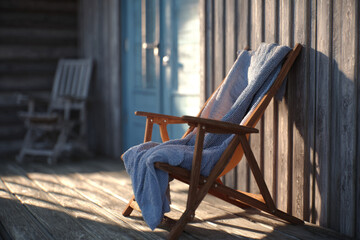 Relaxing moments on a wooden porch with a cozy blanket draped over a chair in soft evening light