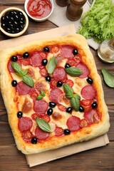 Tasty homemade pizza and ingredients on wooden table, flat lay