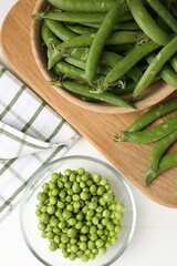 Fresh ripe green peas on white wooden table, flat lay