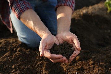 Man holding pile of soil in field, closeup