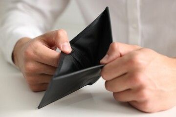 Man with empty wallet at white table, closeup