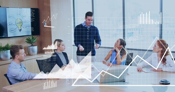 Presenting presenter in navy sweater pointing at display in conference room, with laptop and papers - Powered by Adobe