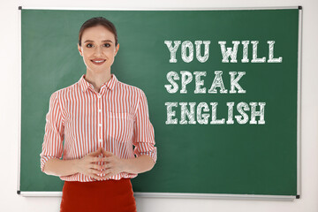 Teacher near green chalkboard with text You Will Speak English. Language course