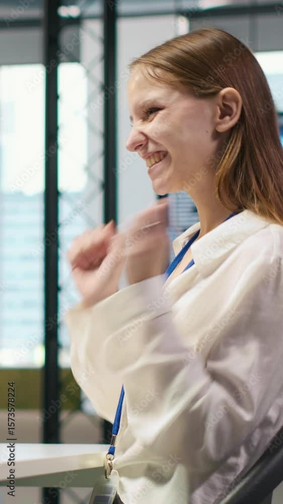 Poster vertical video happy female programmer dancing on office desk chair, pleased after managing to strea