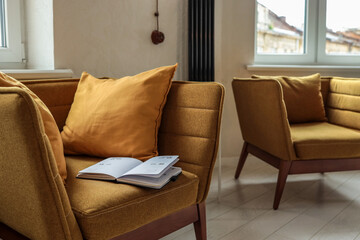 Modern mustard armchair with cozy pillows and an open planner showing August dates, creating a calm, organized space for planning or journaling near a window