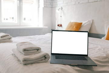 Bright minimalistic bedroom with white brick walls, double bed, laptop on the blanket, and soft...
