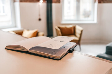 Open planner on kitchen counter in modern loft interior with mustard armchairs, brick walls, and...