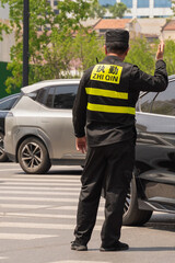 Traffic officer directing vehicles on a busy street in Shanghai during a sunny day