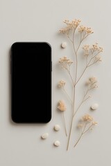 Flat lay of black smartphone with blank screen surrounded by delicate dried flowers and small white pills on neutral background, representing modern wellness, tech, and minimal lifestyle

