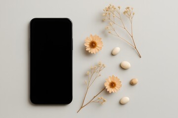 Flat lay of black smartphone with blank screen surrounded by delicate dried flowers and small white pills on neutral background, representing modern wellness, tech, and minimal lifestyle

