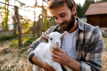 Obraz premium young farmer stroking a small goat kid