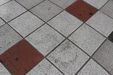 Texture of square paving tile. Pattern of gray, red, and black sidewalk tiles in the street. Concrete pavers close up background.