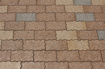 Texture of paving tile. Pattern of gray, brown, and beige sidewalk tiles in the street. Concrete pavers close up background.	