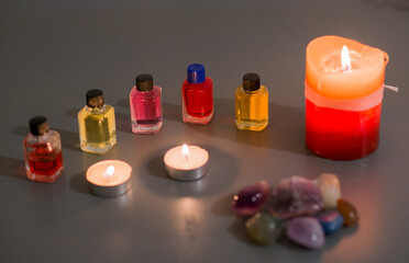 Velas encendidas, aceites esenciales y piedras energéticas sobre superficie gris para rituales de...