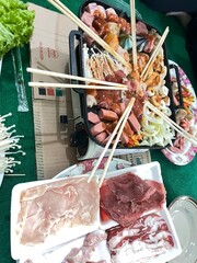 Delicious Feast in Harmony: An overhead perspective reveals an array of delectable foods arranged around a portable grill, ready for a culinary adventure and festive meal.