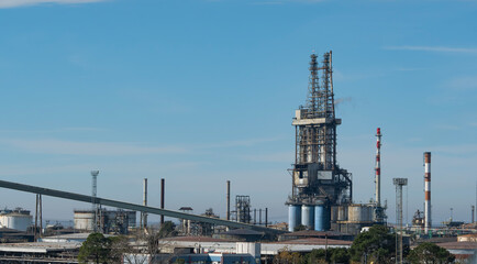 Large industrial refinery complex with distillation towers, storage tanks, and chimneys