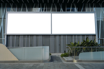 Mockups of two blank white billboards framed by a modern building facade, ideal for advertising