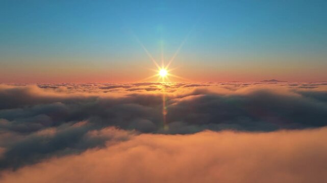 Witness the stunning beauty of a sunrise above soft clouds, with vibrant colors blending in the tranquil morning sky, evoking peace and inspiration for those fortunate enough to see it