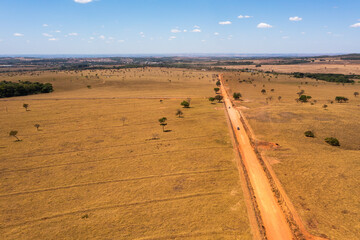 Fototapeta premium Aerial view of cars crossing through a dirt road in the cerrado area. Goiás, Brazil.