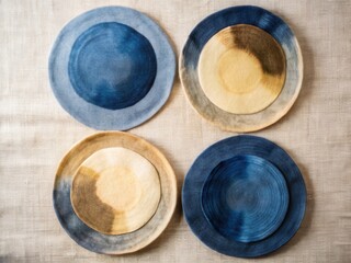 Four handcrafted ceramic plates with unique blue and earth tone watercolor designs
