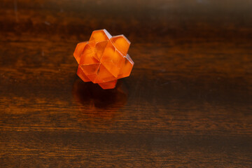 Small transparent orange plastic star used as a puzzle. 
