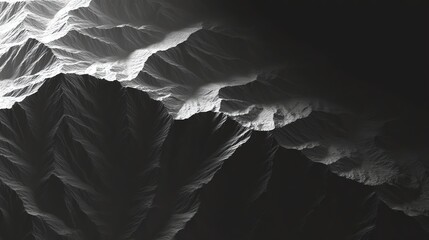 Monochrome aerial view of rugged mountain ridges and deep valleys highlighted by stark light and shadow contrasts.