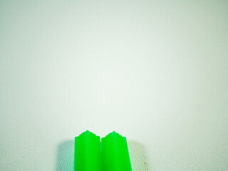 Green plastic straws stand against a white background, an abstract composition with a simple and...