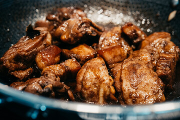 Savory chicken pork adobo simmering in a pan with rich sauce and spices.  with tender pieces marinating in a flavorful sauce. Aromatic spices fill the kitchen.