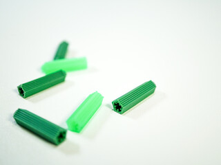 Green plastic wall plugs scattered on a white surface showcasing home improvement and construction...