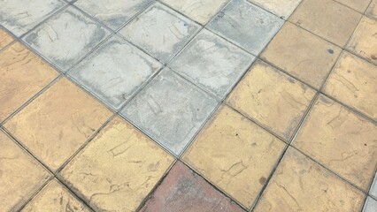 Multi-colored floor tiles with stains and scratches. The courtyard floor is paved with grey,...