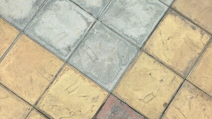 Multi-colored floor tiles with stains and scratches. The courtyard floor is paved with grey,...