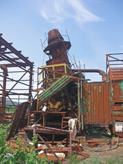 Abandoned powerplant with rusty pipes slanted chimney
