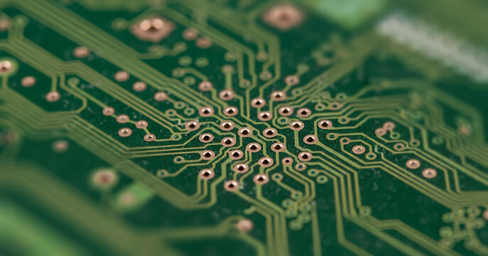 Close-up of a green circuit board with visible traces and solder points, representing typical motherboard structure found in everyday electronics and programmable devices