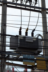 Complex network of power lines surrounding an urban electrical distribution transformer.