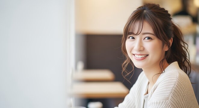 カフェでこちらを見て微笑む若い女性