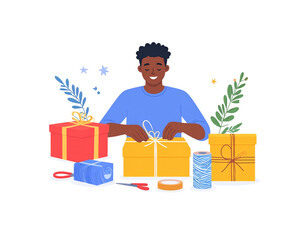 Smiling man wrapping a yellow gift box with white ribbon.