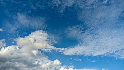 A vibrant sky filled with scattered white clouds against a deep blue background. This serene and...
