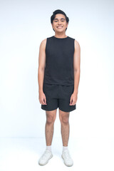 Young Filipino man stands casually with hands at sides, smiling softly in studio while wearing black shorts, sleeveless shirt, and white shoes. © Mdv Edwards