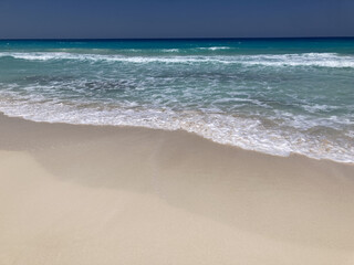 beach view with blue foamy waves and bright clear sky