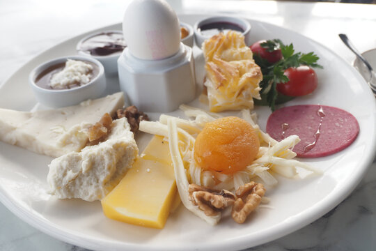 A turkish breakfast platter featuring cheese, eggs, fruits, and spreads.